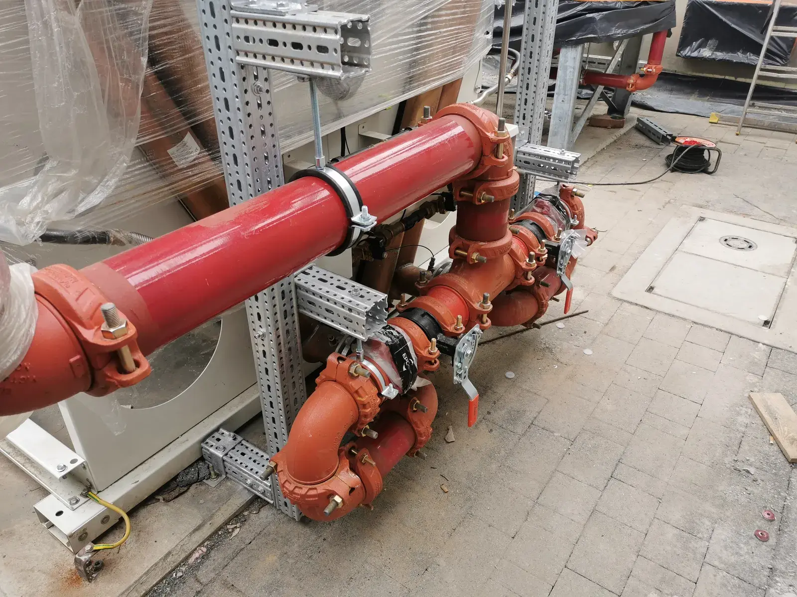 Red grooved pipework with Victaulic couplings and lever valves at the cogeneration unit